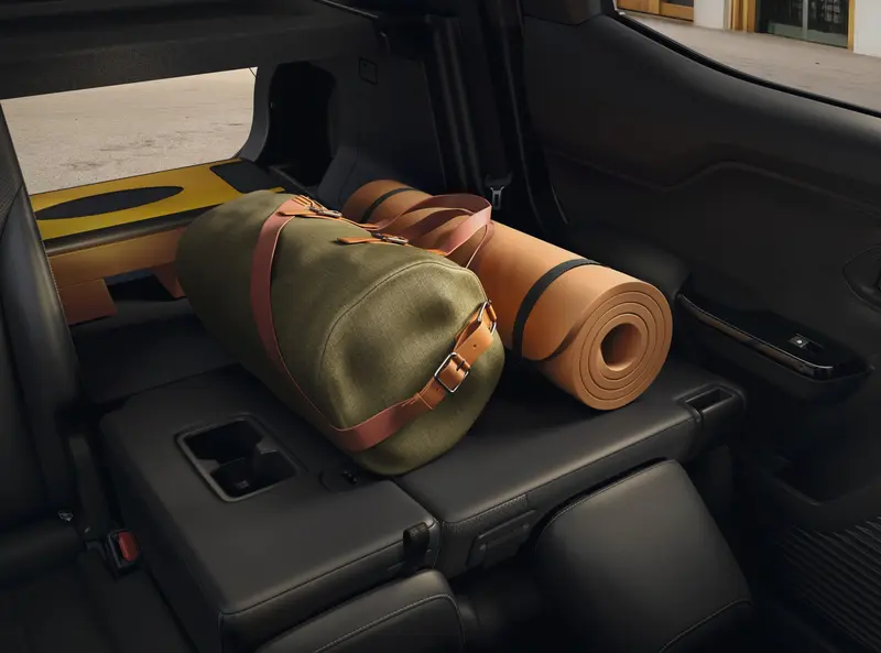 Kofferruimte van de Toyota Urban Cruiser met neergeklapte achterbank, een reistas en een yogamat