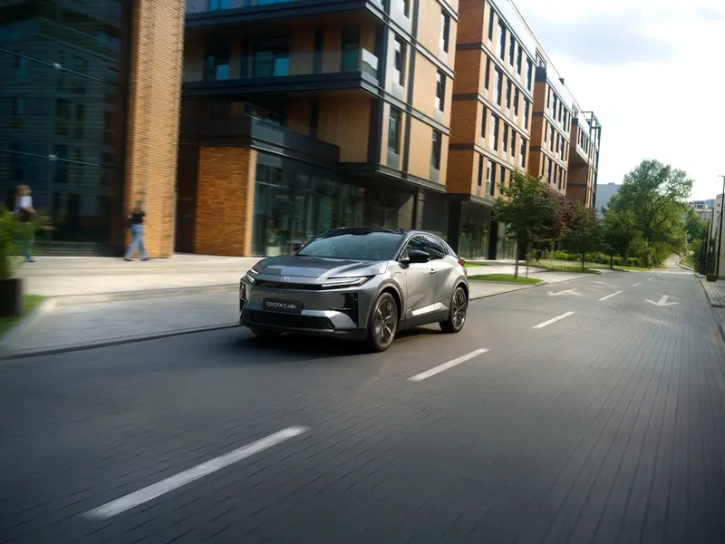 Toyota C-HR+ rijdt door een stadsstraat met moderne gebouwen